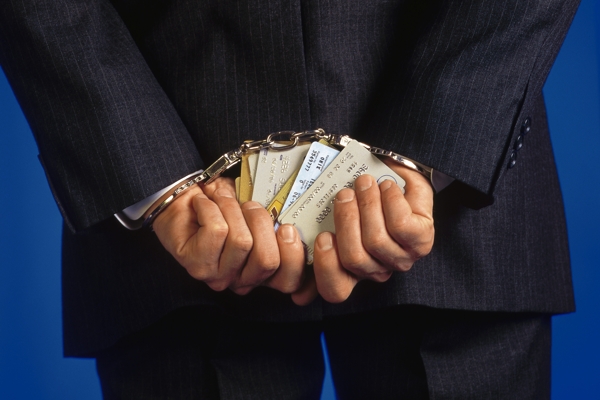 Handcuffed businessman holding credit cards