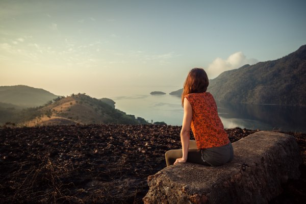 Woman sitting atop hill looking at the mountains