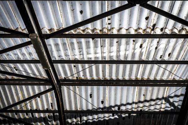 Old corrugated polycarbonate roof with rusty construction