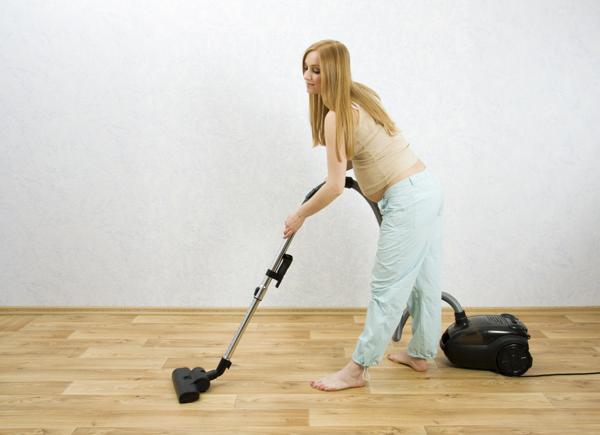 Pregnant woman vacuuming the floor